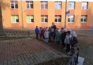 Grupa dzieci wraz z panią Arletą przygląda się pomnikowi poległych podczas II wojny światowe.